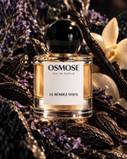 A glass bottle of LE RENDEZ-VOUS with a round black cap, surrounded by vanilla beans and lavender sprigs to evoke a warm, parfum ambré.